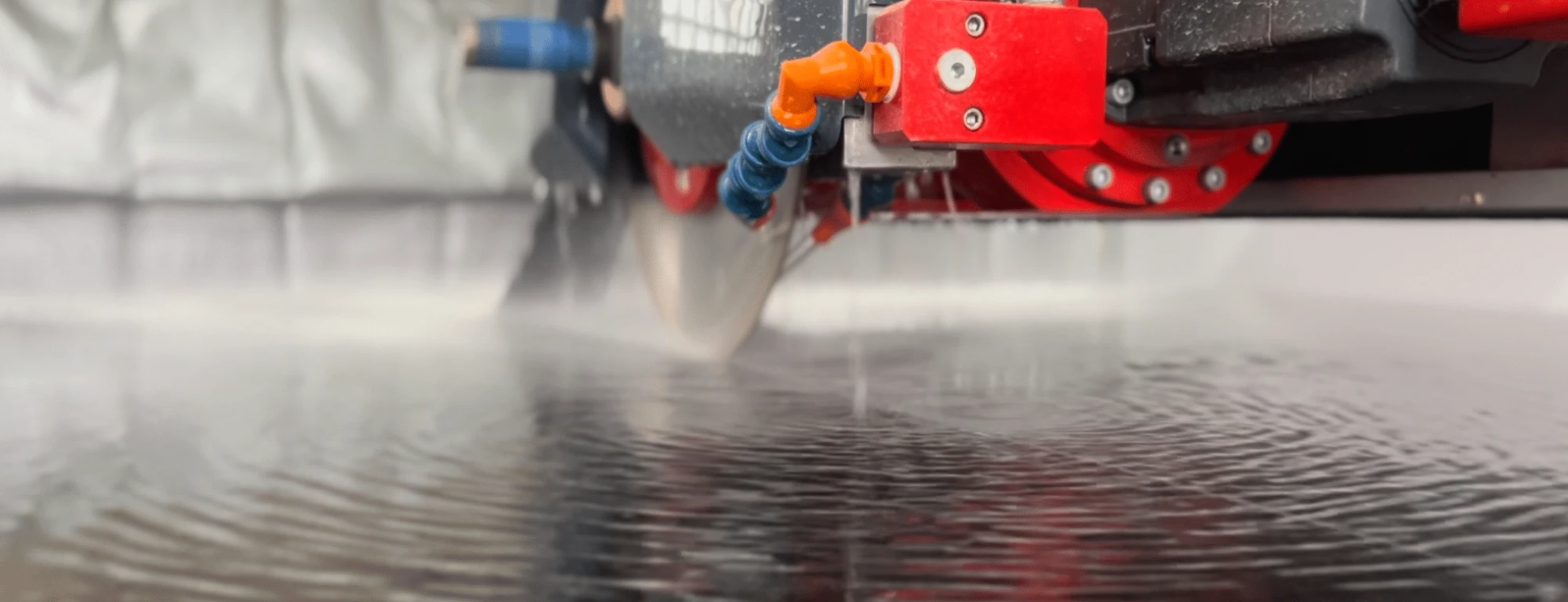 Saw blade cutting a stone slab under a water spray