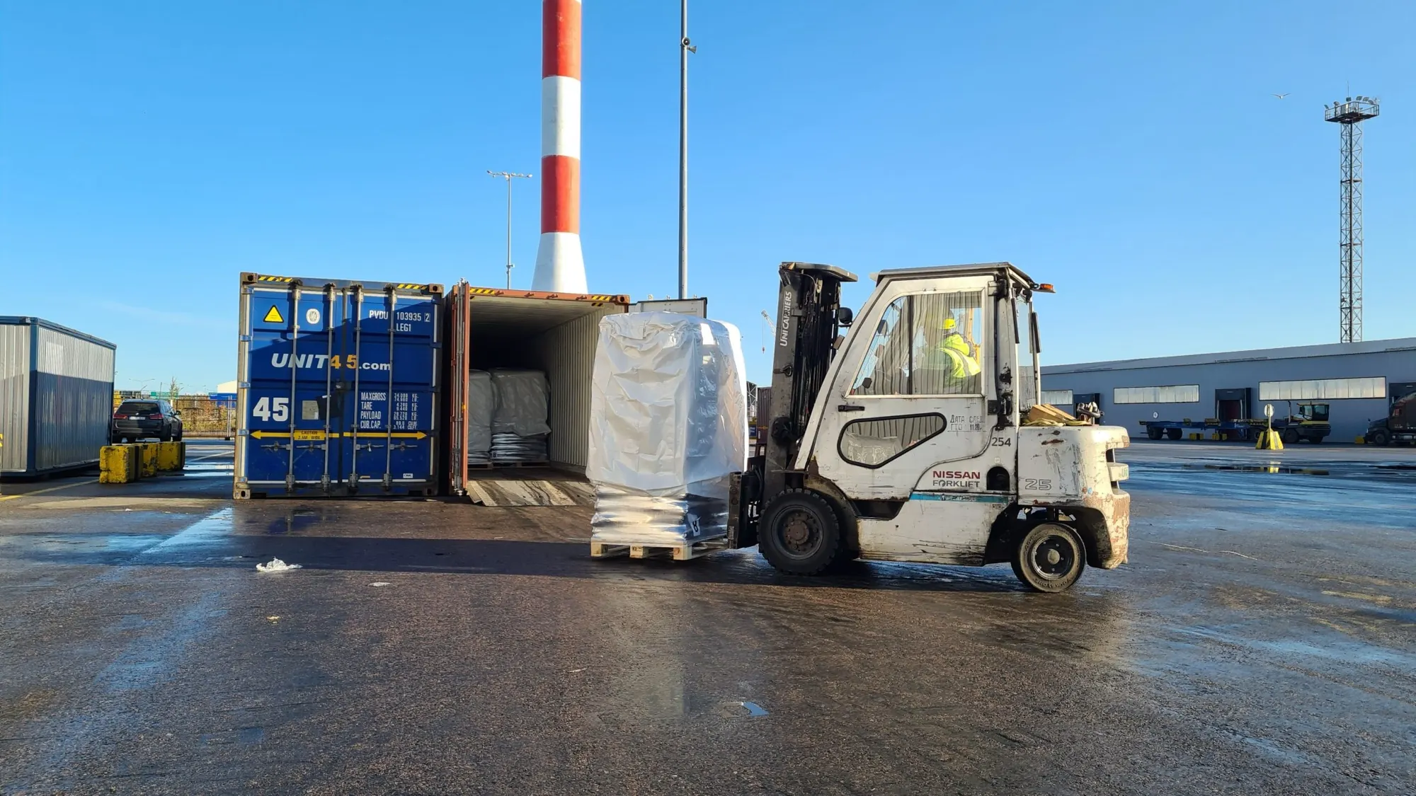 Forklift loading a wrapped pallet into a shipping container
